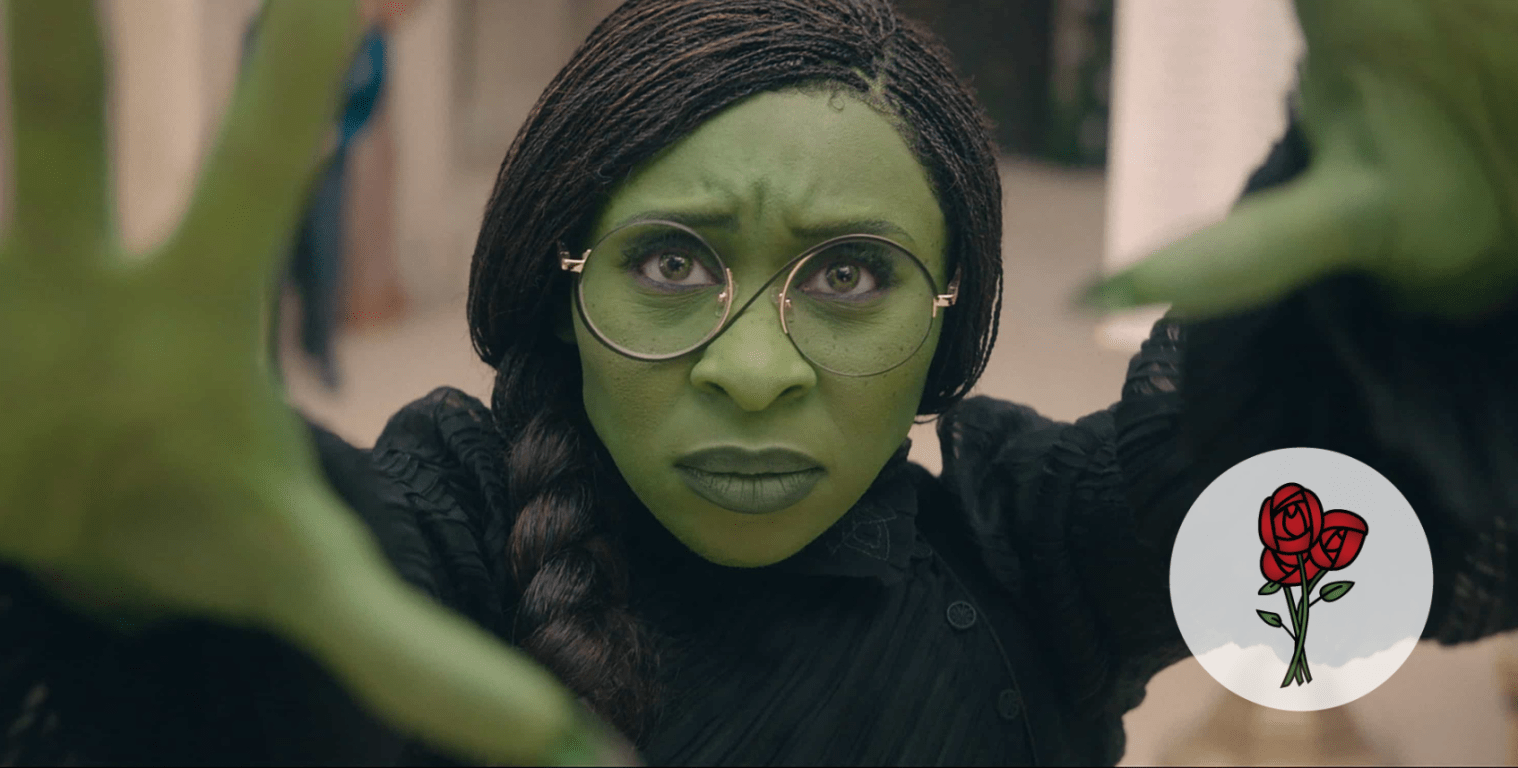 Close up of Cynthia Erivo as Elphaba, the Wicked Witch of the West from Wicked. She has green skin, arms outstretched towards the camera, hair in a long braind over her shoulder. She is staring at us with focus.